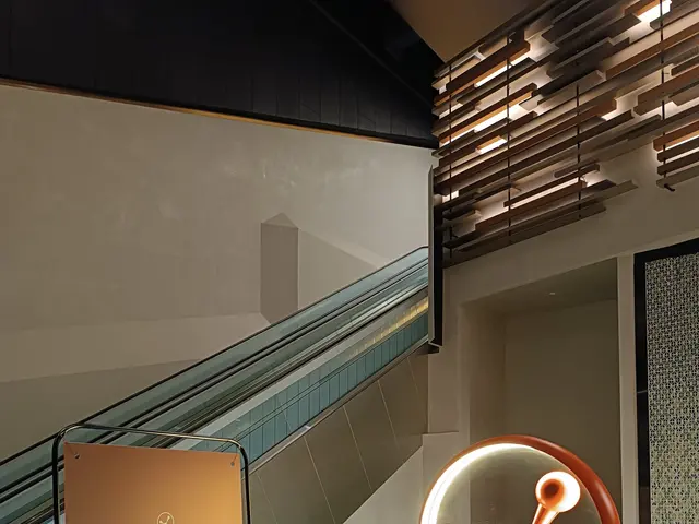 The image shows a large sign in the middle of a building with an escalator in the background. On...