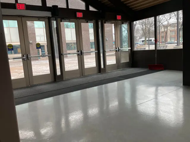 The image shows a large room with a lot of windows and doors, a broomstick on the floor, sign...