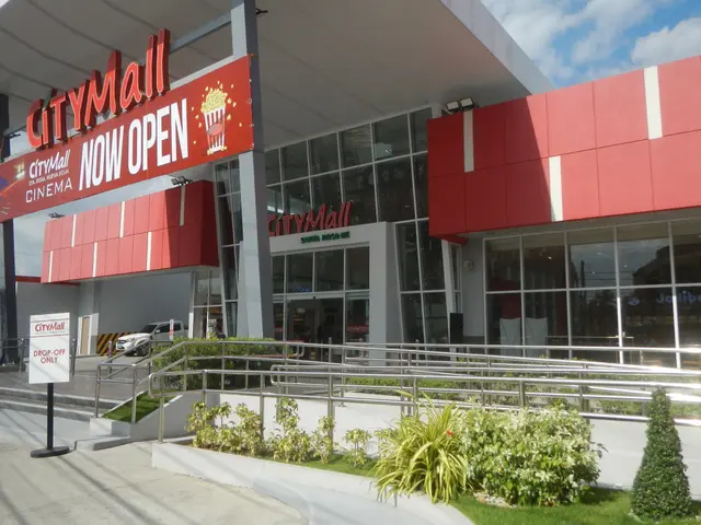 The image shows a city mall with a sign that reads "City Mall Now Open" surrounded by plants,...