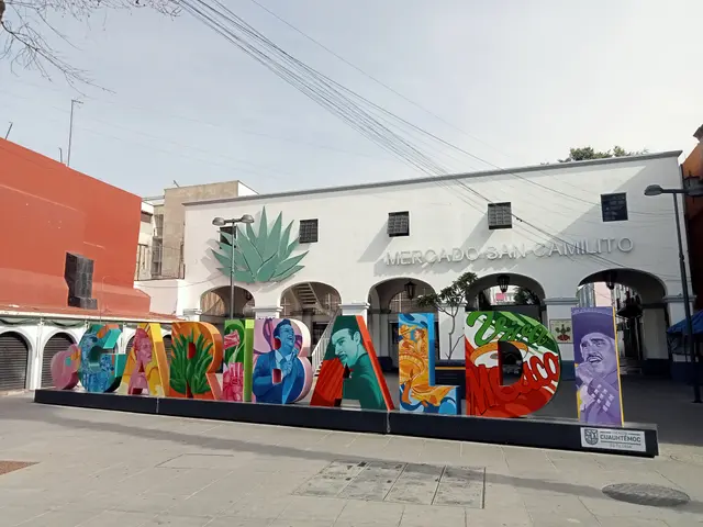 The image shows a vibrant mural on the side of a building in Mexico City, with colorful letters...