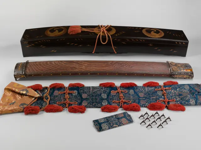 The image shows a Japanese samurai sword with a wooden case and a red tassel, along with a box and...