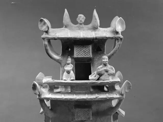 The image shows a black and white photo of a stone sculpture of a pagoda with two statues on top of...