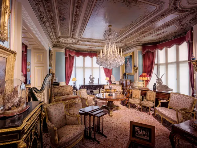 The image shows a living room filled with furniture such as chairs, tables, stools, and a carpet on...