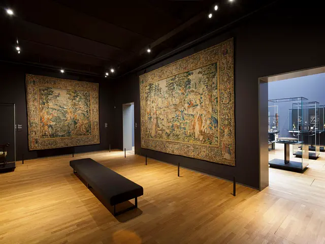 The image shows a room filled with lots of paintings on the walls, a bench on the floor, poles with...