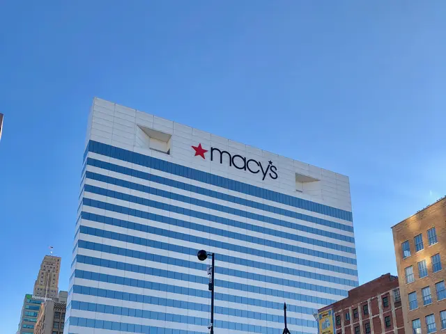 The image shows a bustling city street with vehicles driving on the road, people walking on the...