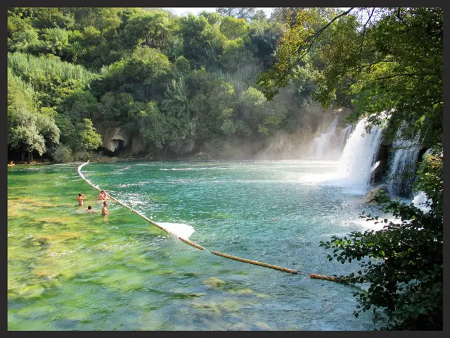 The image shows a group of people swimming in the crystal clear waters of Plitvice Lakes National...