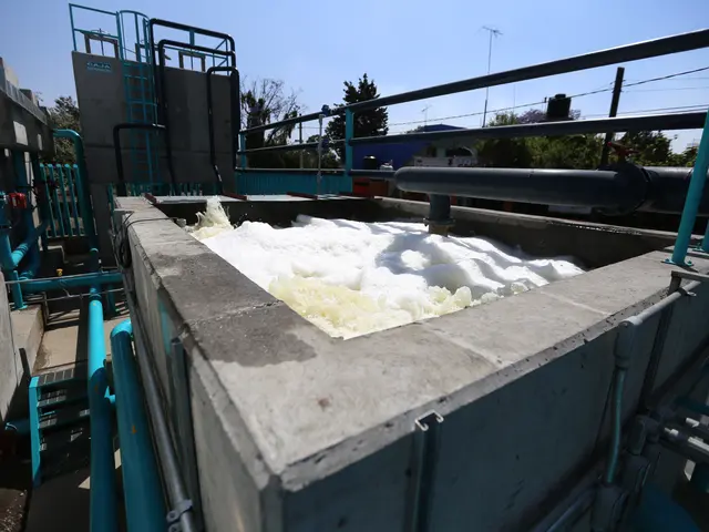 The image shows a large tank filled with lots of white foam sitting on top of a cement wall,...