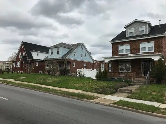 The image shows a row of houses on the side of a road, with windows, doors, steps, railings,...