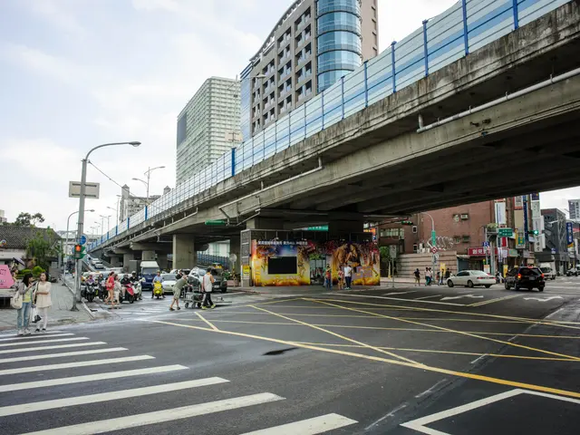 The image shows a bustling city street with a pedestrian bridge over it. There are many vehicles on...