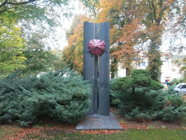 The image shows a large metal sculpture in the middle of a park surrounded by trees, plants, grass,...