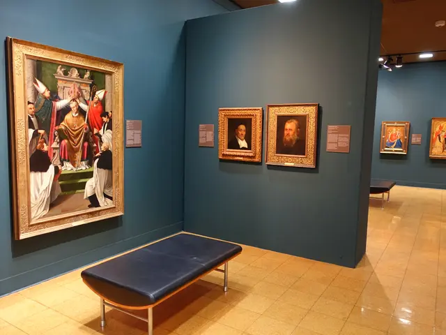 The image shows a room filled with lots of paintings on the walls, a bench on the floor, and photo...