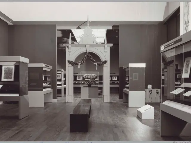 The image shows a black and white photo of a room filled with furniture such as benches, tables,...