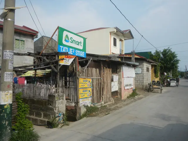 The image shows a small town street with a small building on the side of it. There are electric...