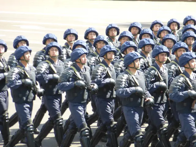 The image shows a group of riot police marching down a street, wearing helmets and holding guns. In...
