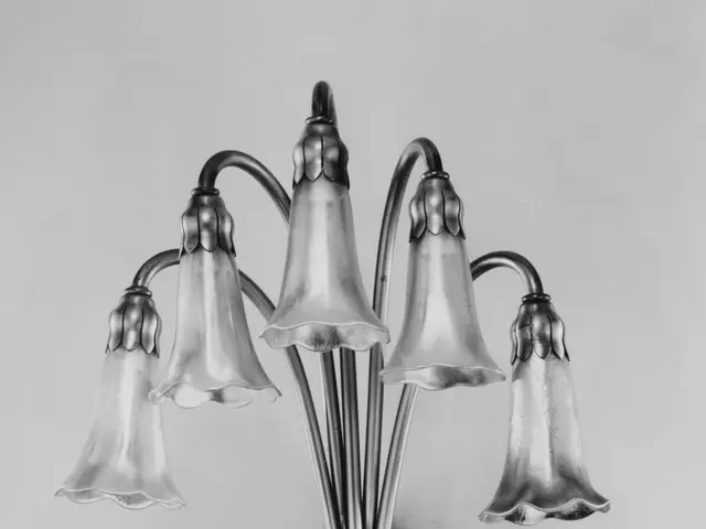 The image shows a black and white photo of a wall sconce with five lights attached to it. The...