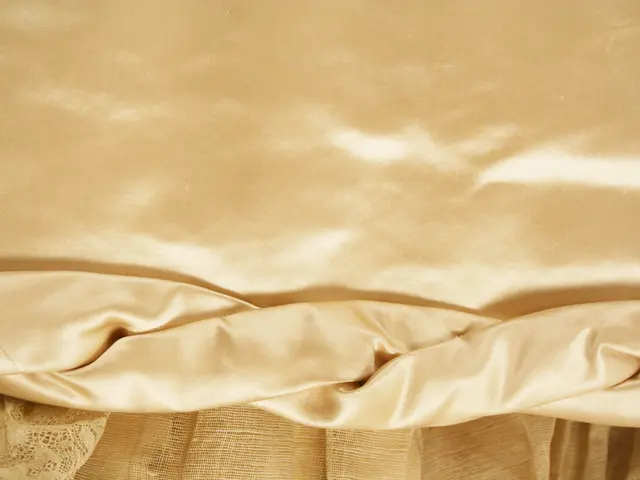 The image shows a close up of a bed with a beige sheet draped over it. The sheet is made of a soft,...