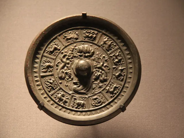 The image shows a metal object on display in a museum, which appears to be a coin with intricate...
