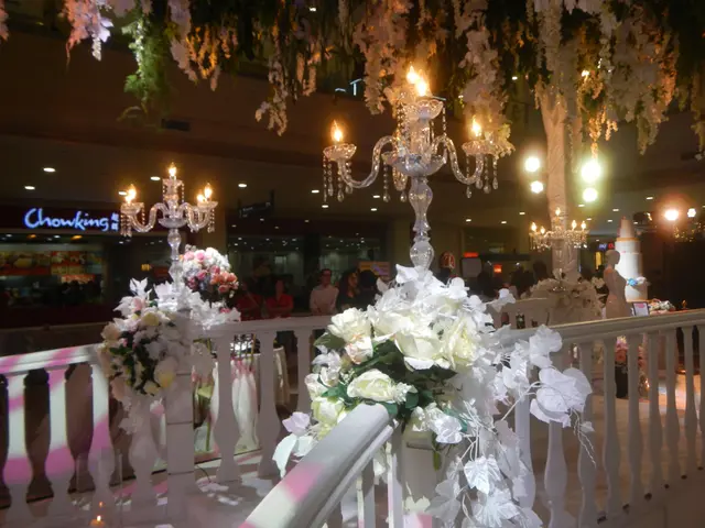 The image shows a wedding ceremony taking place in a mall, with a railing adorned with white...