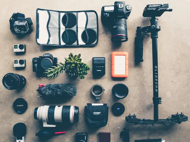 The image shows a variety of camera accessories laid out on the floor, including cameras, a camera...