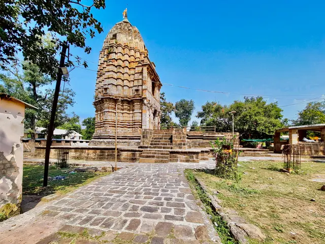 The image shows a stone path leading to a temple in the middle of a field, surrounded by lush green...