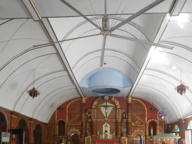 The image shows the interior of a church with wooden pews, flower bouquets on the floor, lights on...