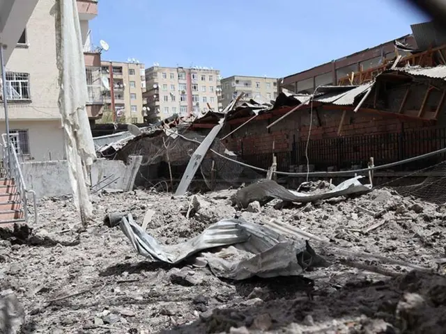 The image shows the aftermath of an Israeli air strike in Gaza City, with the rubble of a building...