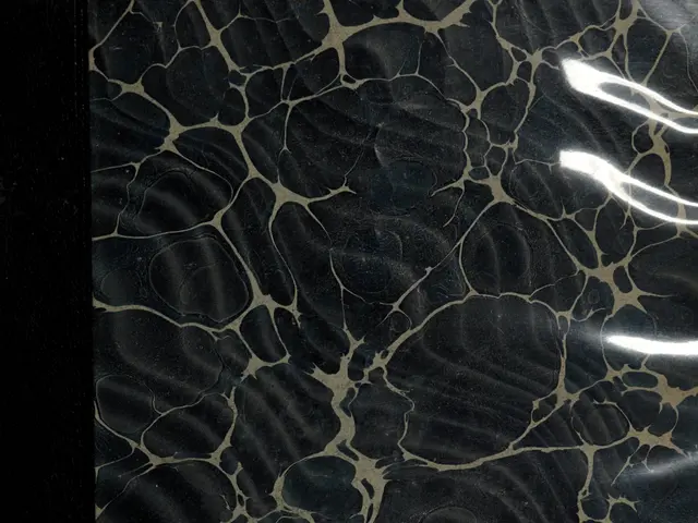 The image shows a close up of a black and gold marble surface with a black background. The marble...