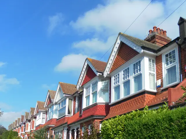The image shows a row of terraced houses on a street in London, England. The houses have glass...