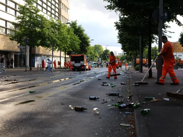 The image shows a group of people in orange uniforms cleaning up trash on the side of a street....