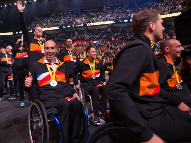The image shows a group of men in wheelchairs on a stage, wearing medals and surrounded by a crowd...