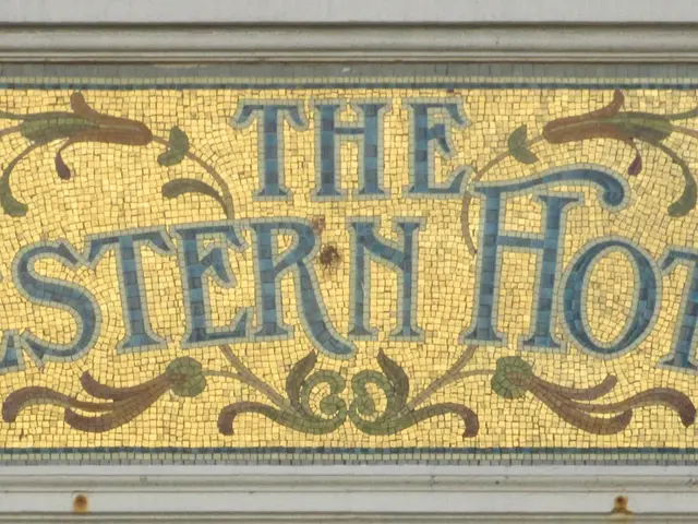 The image shows a wall with a mosaic sign that reads "The Western Hotel" in bold, black lettering....