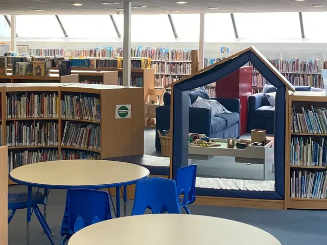 The image shows a library filled with lots of books on the racks, tables and chairs, sofas with...