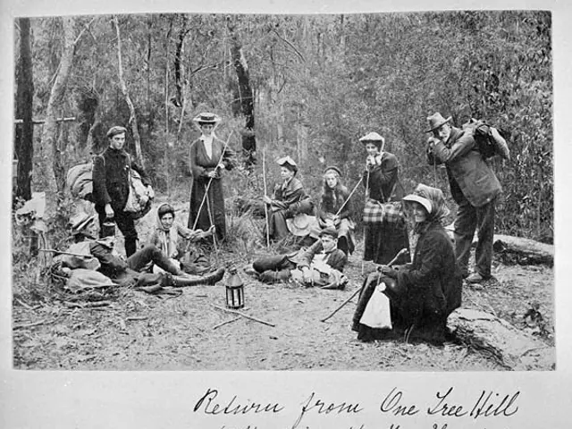 The image shows a group of people sitting around a campfire in the woods. Some of them are wearing...