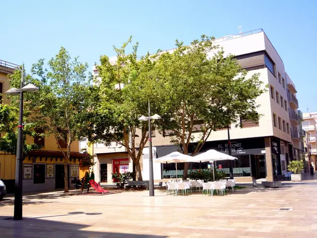 The image shows a city street with buildings, trees, street poles, street lights, motor vehicles on...