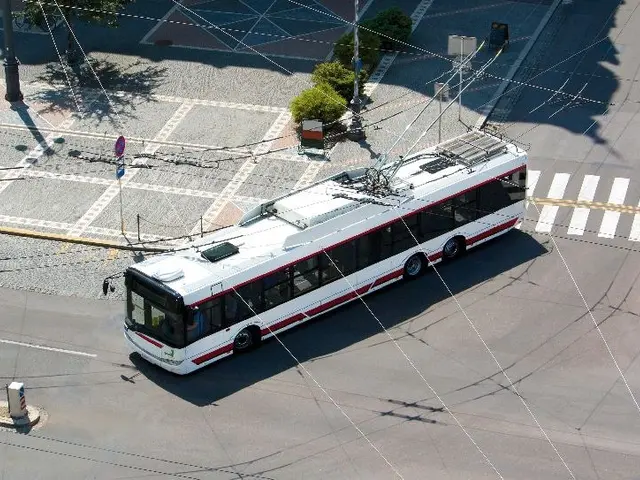 The image shows a white and red bus driving down a street next to a crosswalk, surrounded by...