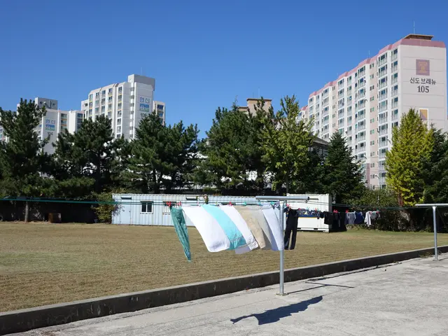 The image shows clothes hanging out to dry on a clothes line in front of a building, with a road at...
