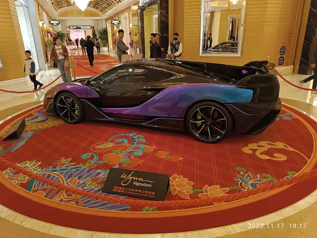 The image shows a purple and black car parked in the lobby of a hotel, surrounded by a group of...