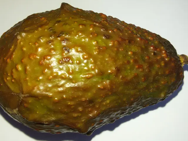 The image shows a close up of a custard apple on a white surface. The fruit is a vibrant green...