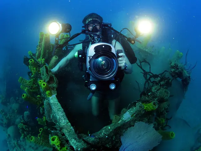 The image shows a scuba diver taking a photo of a shipwreck in the ocean. The diver is wearing a...