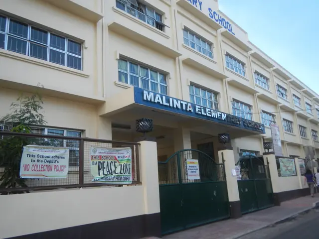The image shows Malinta Elementary School in Lagos, Nigeria. It is a building with windows, a name...
