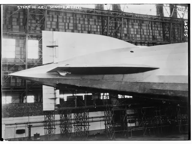 The image shows a black and white photo of a stealth bomber in a hangar, surrounded by metal rods...