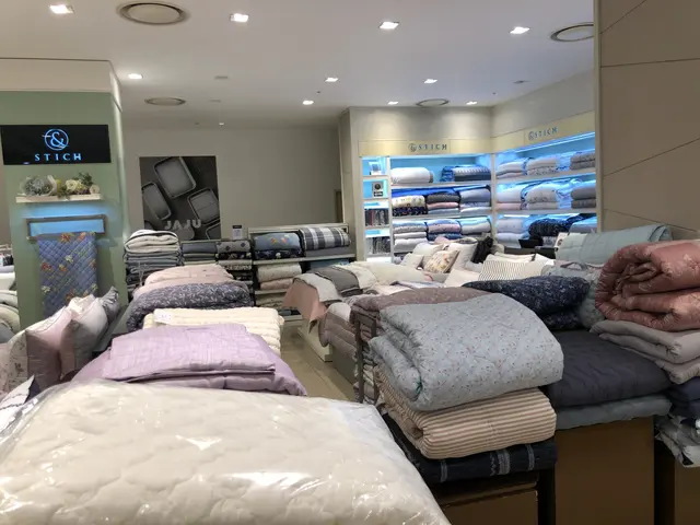 The image shows a store filled with lots of different types of bedding, including mattresses,...