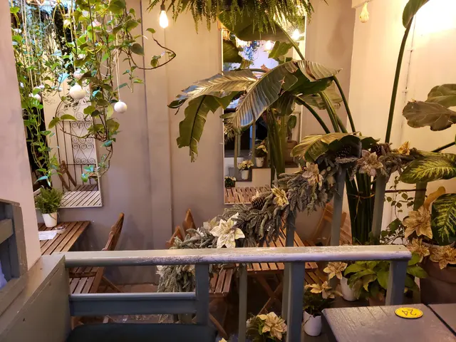 The image shows a room filled with lots of plants and potted plants, as well as chairs, tables, a...
