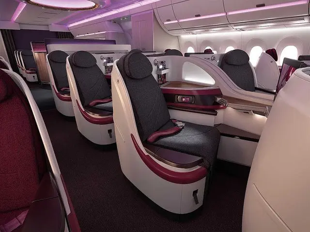 The image shows the interior of a Qatar Airways A380 Business Class cabin, with comfortable seats,...