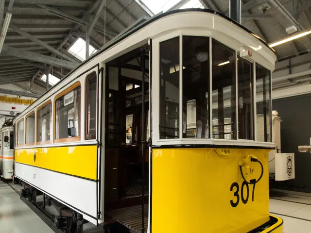 The image shows a yellow and white tram on display in a museum. The tram is on the floor and there...