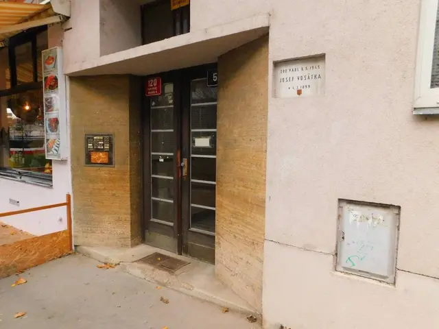 The image shows a building with a door and windows on the side of it, a signboard with some text on...