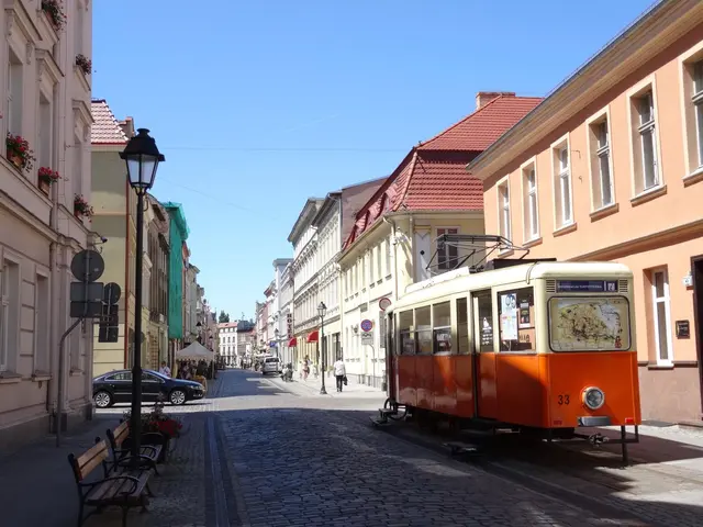 The image shows an orange tram on a cobblestone street in the old town of Tallinn, Estonia. On...