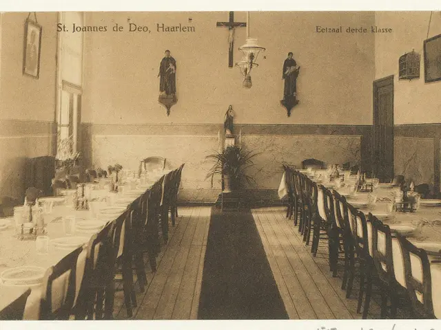 The image shows an old photo of a long dining room with tables and chairs arranged around it. On...