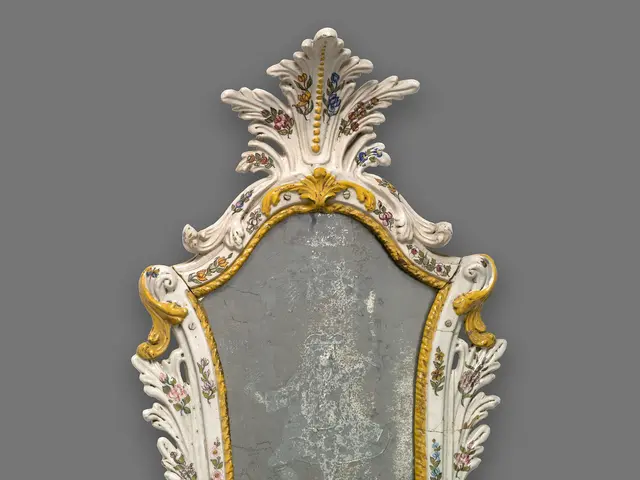 The image shows an ornate mirror with a white and gold frame on a gray background. The frame is...