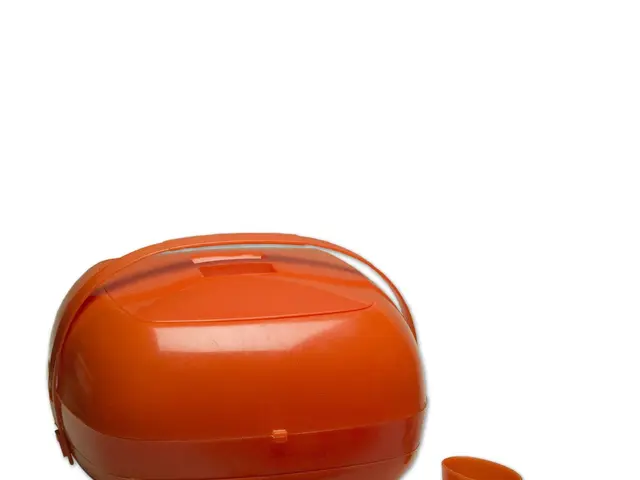 The image shows an orange lunch box with a set of orange plastic plates, spoons, forks, and glasses...